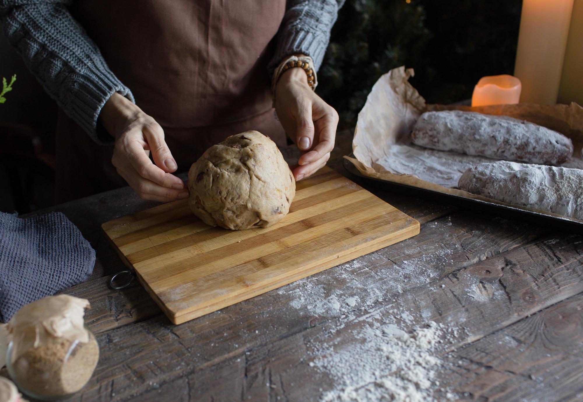 Hands kneading dough on wooden board